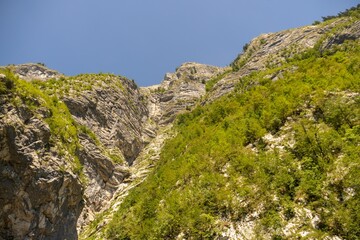 Low angle shot of grassy and mossy rugged cliffs under a clear sky