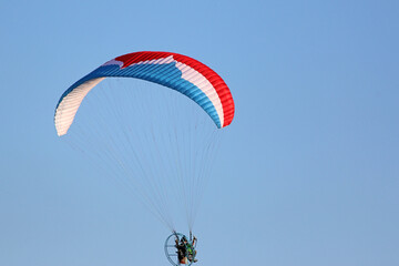 Paramotor pilot flying in a blue sky	