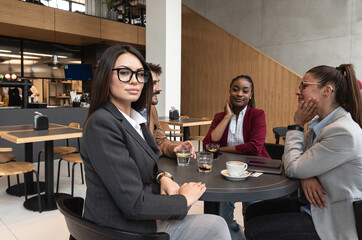 Group of young freelancers real estate agents have business meeting in cafeteria discussing about prices and situation on the rental and selling market of houses and apartments. Selective focus