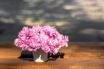 A bouquet of delicate pink carnations in a white decorative bucket on a blurred background. Place for an inscription. Selective focus.