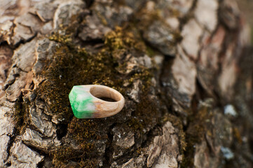 Photo of a ring made of epoxy resin lying on a texture cut of a tree. Eco-friendly material to create beautiful things. Bright unusual gift for a girl. Epoxy resin is often used for decor.