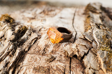 Photo of a ring made of epoxy resin lying on a texture cut of a tree. Eco-friendly material to create beautiful things. Bright unusual gift for a girl. Epoxy resin is often used for decor.