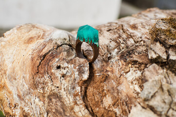 Photo of a ring made of epoxy resin lying on a texture cut of a tree. Eco-friendly material to create beautiful things. Bright unusual gift for a girl. Epoxy resin is often used for decor.