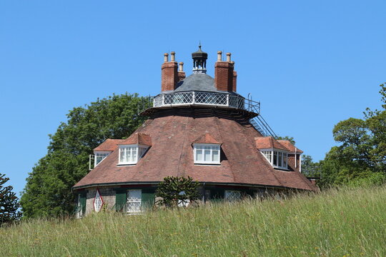 The roof of an unusual historic sixteen sided house on a beautiful sunny summers day in Devon, England seen from across the meadow garden.