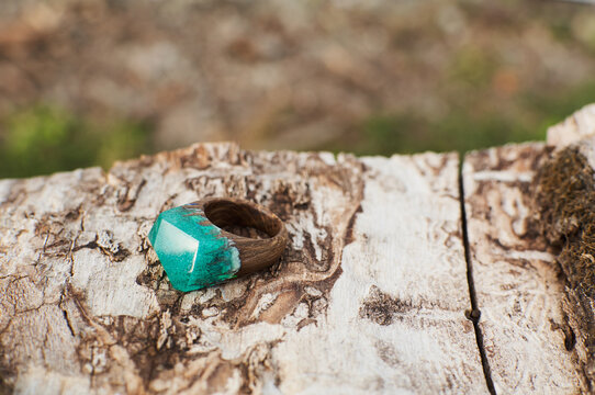 Photo of a ring made of epoxy resin lying on a texture cut of a tree. Eco-friendly material to create beautiful things. Bright unusual gift for a girl. Epoxy resin is often used for decor.