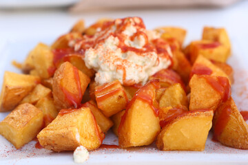 baked potato with garlic sauce aioli and tomato ketchup on square plate with human hands closeup photo