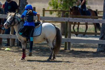 Little Girl that gets back in th saddle of a Pony during Pony competition at the Equestrian School