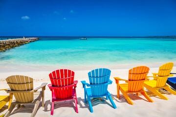 Fototapeta na wymiar Idyllic beach with rustic adirondack chairs in Aruba, Dutch Antilles