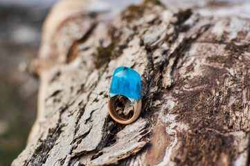 Photo of a ring made of epoxy resin lying on a texture cut of a tree. Eco-friendly material to create beautiful things. Bright unusual gift for a girl. Epoxy resin is often used for decor.