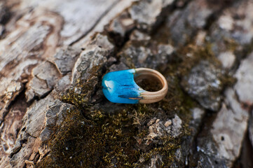 Fototapeta na wymiar Photo of a ring made of epoxy resin lying on a texture cut of a tree. Eco-friendly material to create beautiful things. Bright unusual gift for a girl. Epoxy resin is often used for decor.