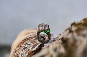 Photo of a ring made of epoxy resin lying on a texture cut of a tree. Eco-friendly material to create beautiful things. Bright unusual gift for a girl. Epoxy resin is often used for decor.