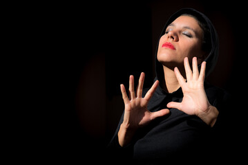 woman in the dark, sensual expression, open hands, black background