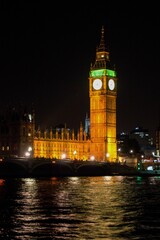 Vertical view of the illuminated Big Ben by the river at night