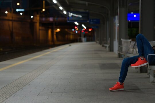 Person sitting in red sneakers in the train station. - Powered by Adobe