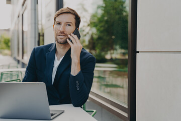 Outdoor shot of successful man executive worker calls someone via smartphone