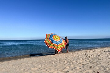 A man holding an open parasol on the beach © Mounir Taha/Wirestock Creators