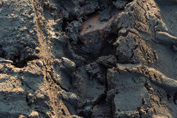 A deep car track on a Russian dirt road after rain. The imprint of car tires on the dirt. Dried mud on the roads in the village.
