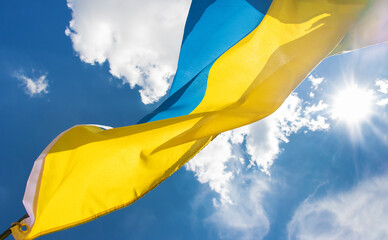 The national flag of Ukraine is flying on the blue sky with sun