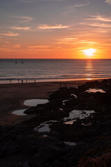 Fototapeta na wymiar sunset over the sea people walking on the beach dark reflection boats horizon sand