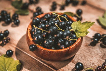 black currants in a bowl on a wooden background. berries, summer, vitamins, healthy natural food. top view. selective focus