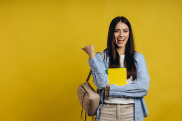Successful young college student holding books and shaking hands on yellow background. The concept...