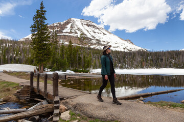 Woman walking Lake Trail surrounded by Mountains and Trees in Amercian Landscape. Spring Season....