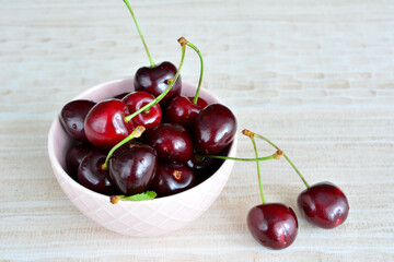 dark garden cherries in pink bowl isolated, close-up