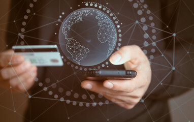Man holds a bank card and a phone, planet icon added, closeup view.
