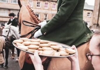 Woman holding a tray with biscuits by a horseman during the Heythrop Hunt Boxing Day - obrazy, fototapety, plakaty