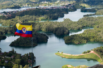 Bandera de Colombia ondeando sobre el lago de Guatapé - obrazy, fototapety, plakaty