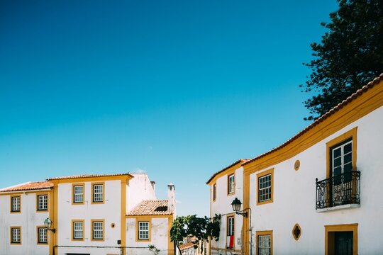 Aerial view of yellow and white building facades under blue bright sky in Abrantes