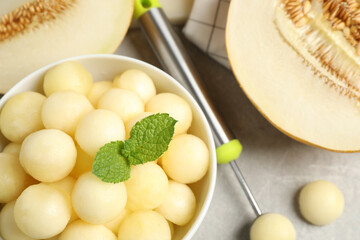 Melon balls and mint in bowl on light grey table, top view