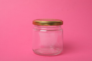 Closed empty glass jar on pink background