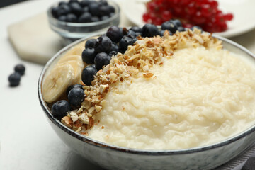 Delicious rice pudding with banana, blueberries and almond on light table, closeup