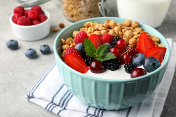 Bowl with tasty granola and berries on light grey table, closeup. Healthy meal