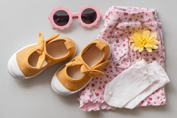 Stylish child clothes, shoes and accessories on grey background, flat lay