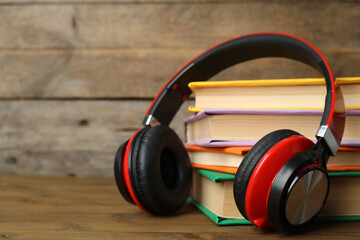 Books and modern headphones on wooden table, closeup