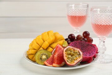Delicious exotic fruits and wine on white wooden table