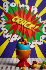 Vertical shot of the pop art egg with candies on a colourful background
