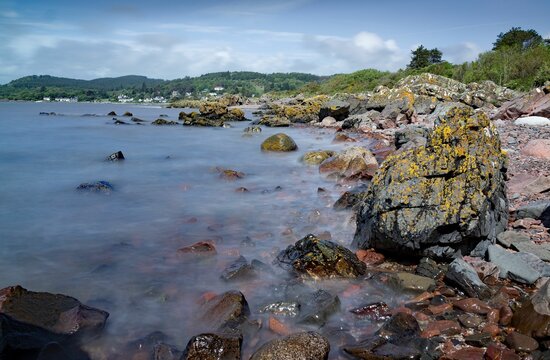 Rocky beach with calm waves in the village of Rockcliffe during the daytime