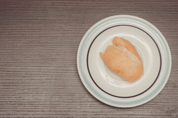 French bread, individual portion on white ceramic plate with isolated wooden background. top view.