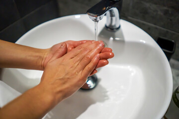 Woman is washing her hands with a soap.