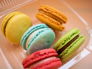 French dessert with coffee. Colorful macaroni or macaroons on an orange background.