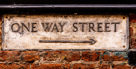 Old Weathered One Way Street Sign on a Wall with Arrow indicating Left to Right
