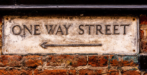 Old Weathered One Way Street Sign on a Wall with Arrow indicating Right to Left