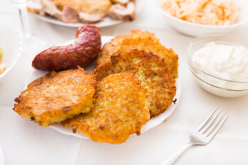 Potato pancakes with fried sausage on white plate