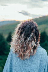 girl on the background of mountains forest and sunset looks into the distance travel hike...