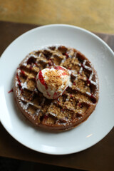 Top down view of an ice cream waffle on white plates on wooden table