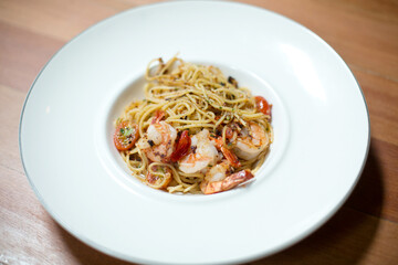 Spicy Prawn AglioOlio on wooden table in find dining plate