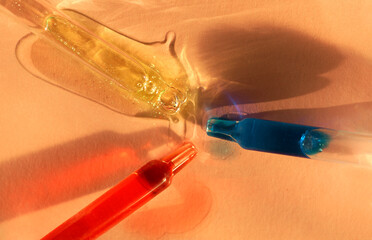 Three pipettes with fluid serum, oil, face gel cleaner. Cosmetics and healthcare concept closeup....